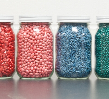 Jars filled with treated seeds in varying colors.